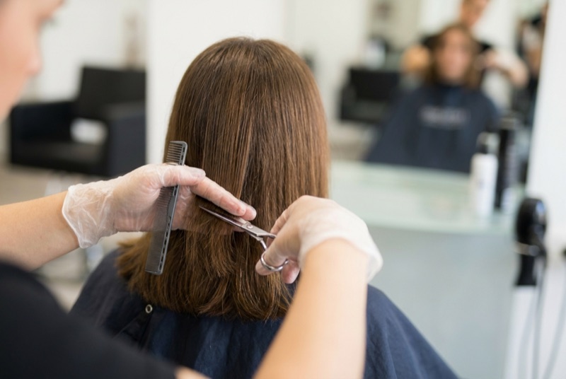 Hände einer Friseurin beim Schneiden schulterlanger Haare